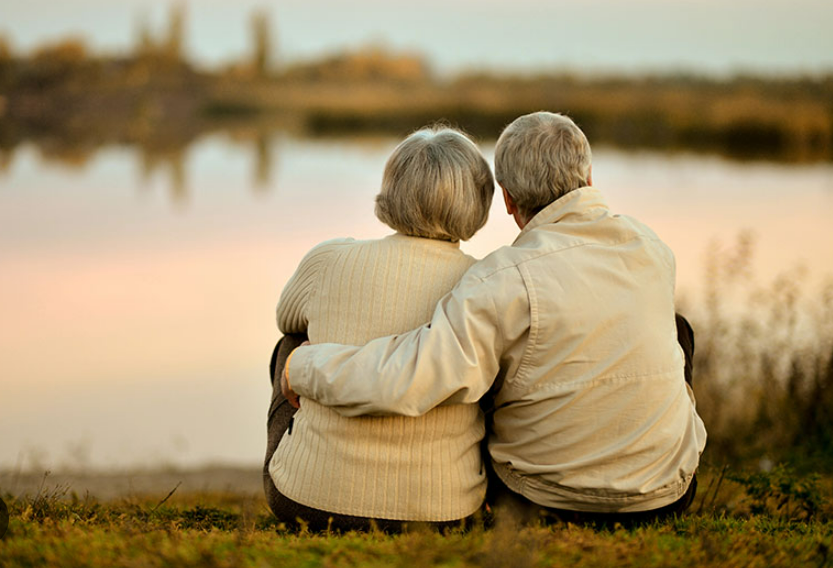 Mature couple sitting together looking out at a lake