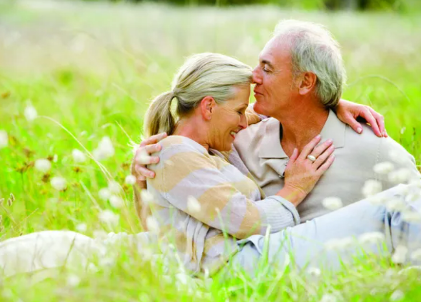 Mature couple embracing outdoors in a grassy field