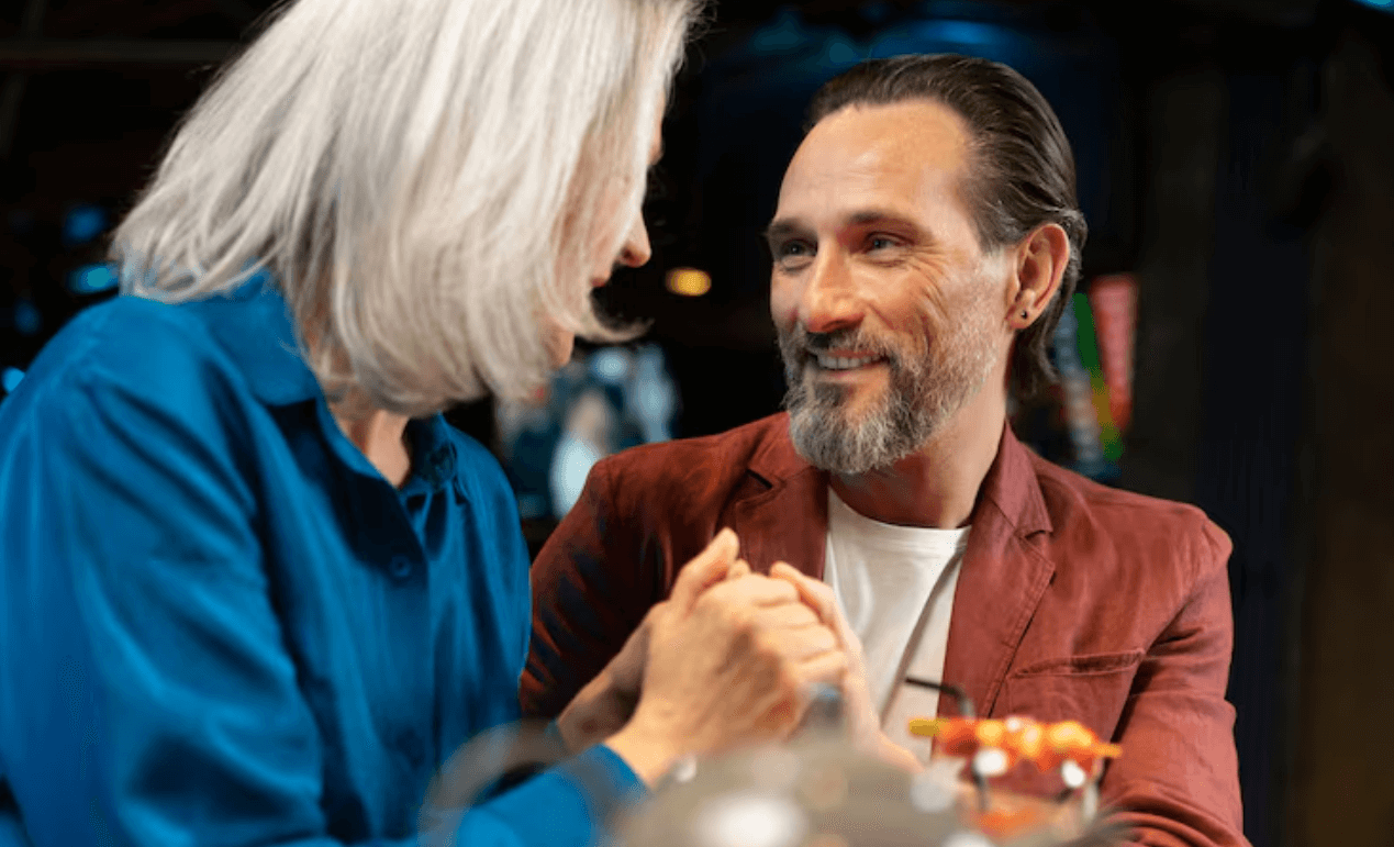 Mature couple in conversation, hands clasped at a table
