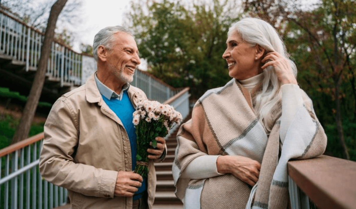 Mature couple holding flowers and smiling on a bridge
