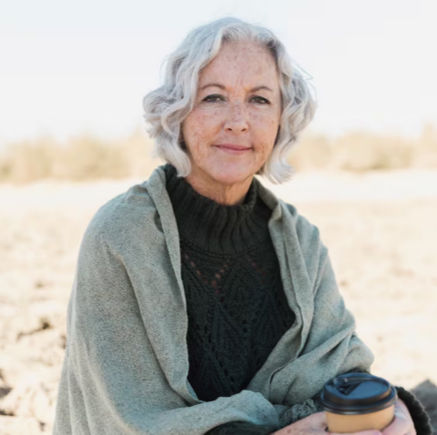 Mature woman sitting outdoors holding a warm drink